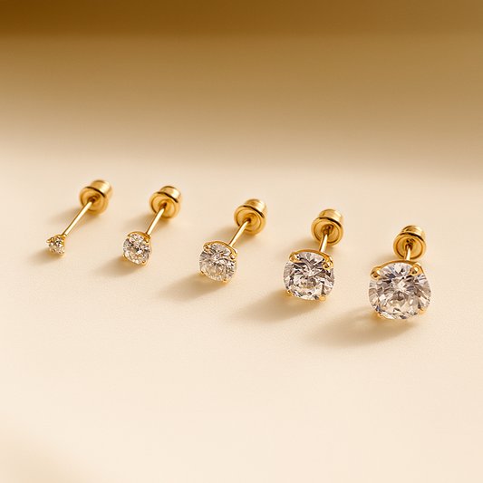 Set of gold earrings with clear gemstones on a beige background